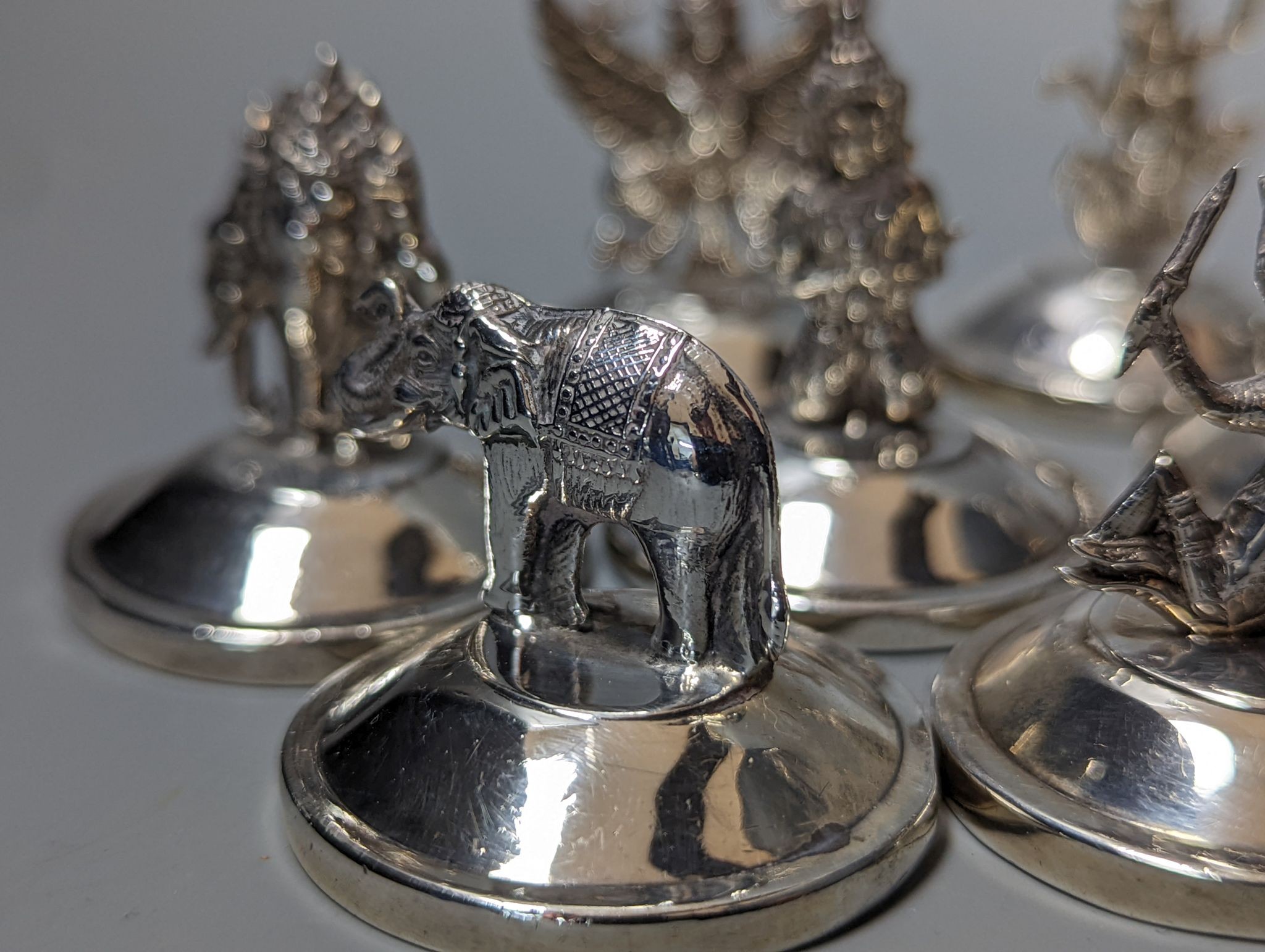 Sixteen assorted Siamese sterling mounted menu holders, modelled with figures, elephant, etc.